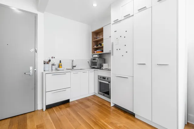 a kitchen with cabinets stainless steel appliances and wooden floor