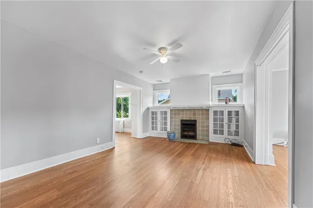 an empty room with wooden floor fireplace and windows