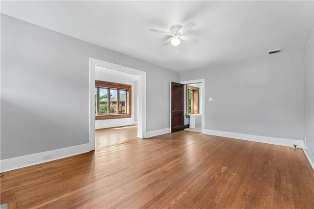 a view of an empty room with window and wooden floor