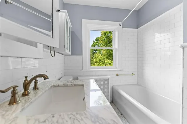 a bathroom with a tub a sink and a window
