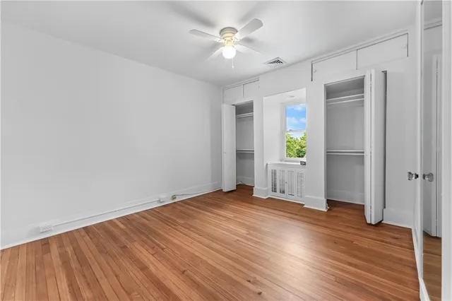 an empty room with wooden floor and a ceiling fan