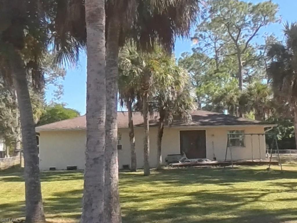 231 14th Street Northeast Naples, FL 34120 - Photo 4 of 13 Back of house featuring a yard and stucco siding