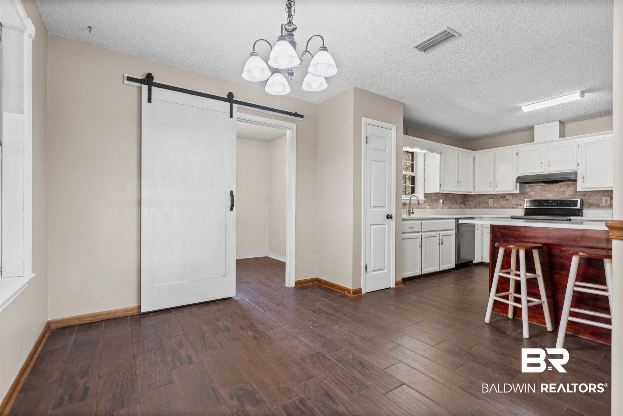 180 Creax Road Axis, AL 36505 - Photo 5 of 35 Kitchen with a barn door, light countertops, white cabinetry, a chandelier, and pendant lighting