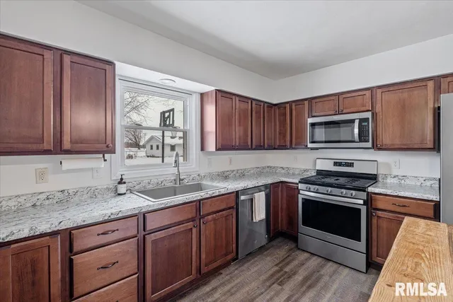 a kitchen with granite countertop a sink counter top space stainless steel appliances and cabinets