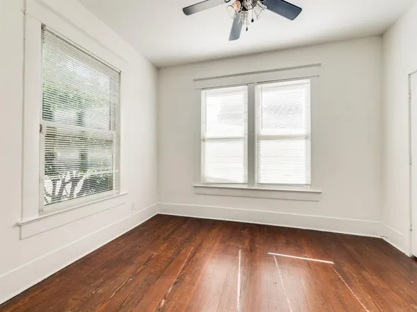 an empty room with wooden floor and windows
