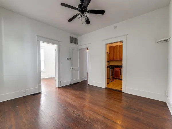an empty room with wooden floor ceiling fan and windows