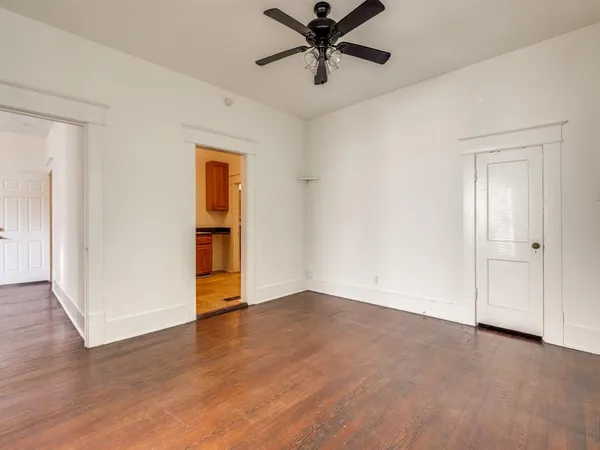 an empty room with wooden floor closet and windows