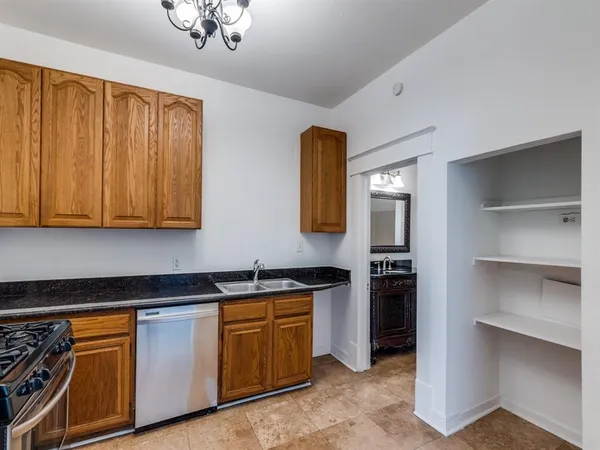 a kitchen with granite countertop stainless steel appliances a stove refrigerator and cabinets