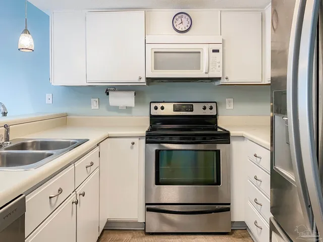 a kitchen with granite countertop white cabinets stainless steel appliances and a sink
