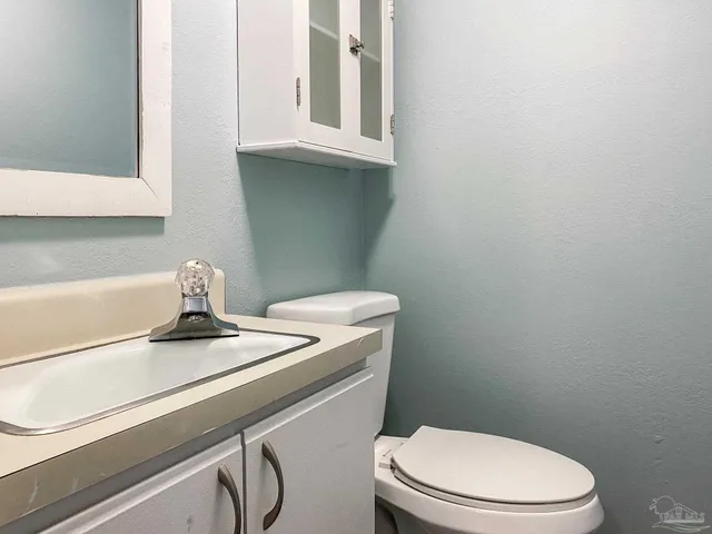 a bathroom with a granite countertop toilet sink and mirror