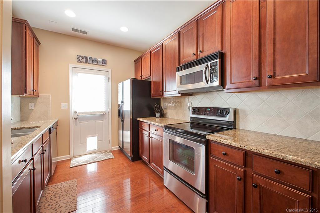1903 Travertine Lane, Unit 1903 Fort Mill, SC 29708 - Photo 6 of 16 a kitchen with granite countertop wooden cabinets stainless steel appliances and a window
