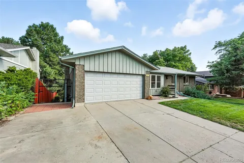 front view of house with a yard and trees all around