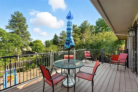 a balcony with wooden floor table and chairs