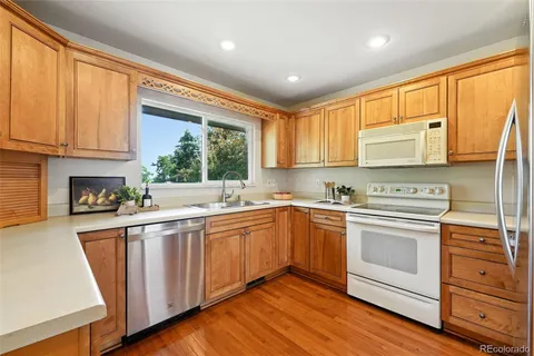 a kitchen with stainless steel appliances granite countertop a stove a sink and white cabinets with wooden floor