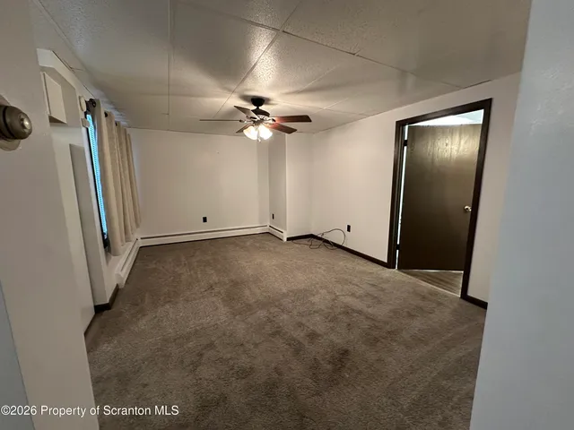 an empty room with windows and fan