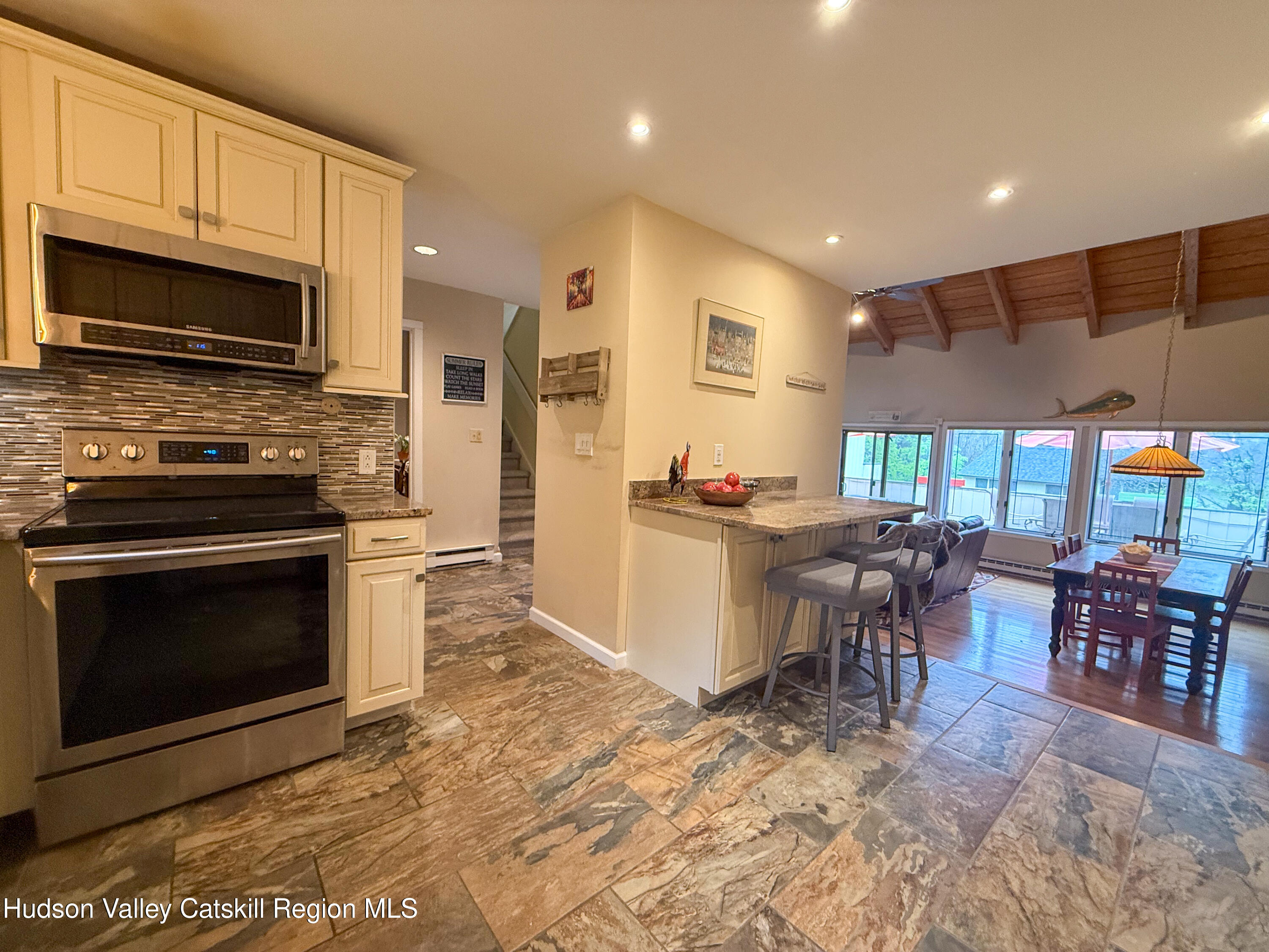 300 Pines Drive, Unit 446 Roxbury, NY 12421 - Photo 20 of 49 a kitchen with stainless steel appliances granite countertop a stove top oven a sink dishwasher a dining table and chairs with wooden floor