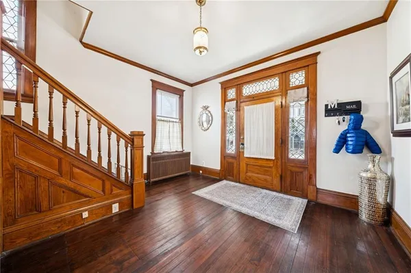 a view of front door with hallway and wooden floor