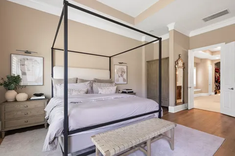 a bedroom with a bed a large window and potted plant on the table