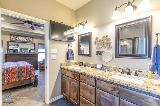a en suite bathroom with a granite countertop sink and a mirror