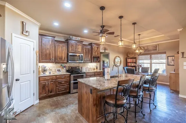 a large kitchen with granite countertop a stove a sink a dining table and chairs