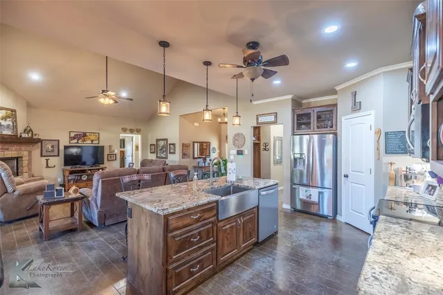 a large kitchen with stainless steel appliances kitchen island granite countertop a refrigerator a oven a island and couches with wooden floor