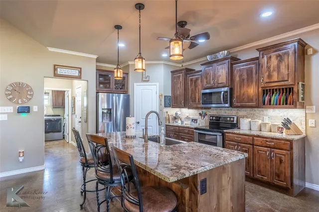 a kitchen with stainless steel appliances granite countertop a kitchen island a stove a table and chairs