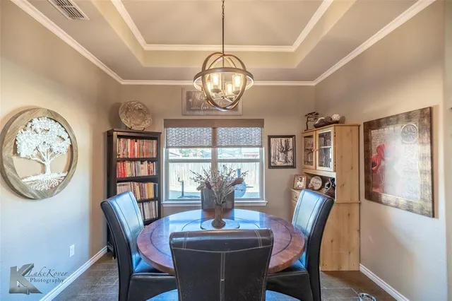 a view of a dining room with furniture a large window and a chandelier