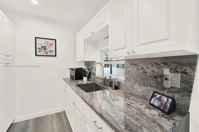 a kitchen with granite countertop a sink and white cabinets