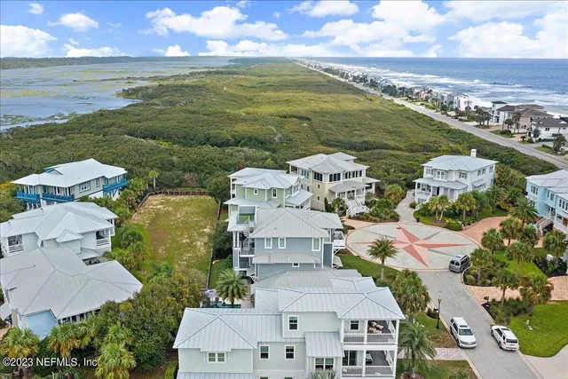 an aerial view of residential houses with outdoor space and ocean view