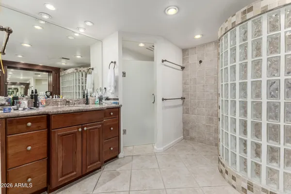 a bathroom with a granite countertop bathtub shower sink vanity and mirror
