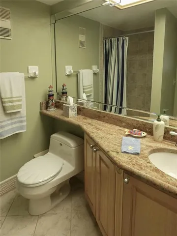 a bathroom with a granite countertop toilet sink and mirror