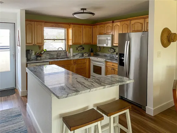 a kitchen with granite countertop a refrigerator a stove a sink cabinets and wooden floor