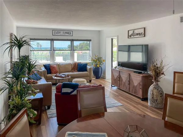 a living room with furniture a flat screen tv and a floor to ceiling window