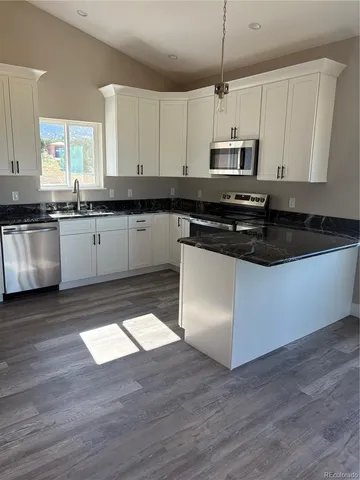 a view of a kitchen with granite countertop wooden floor and stainless steel appliances