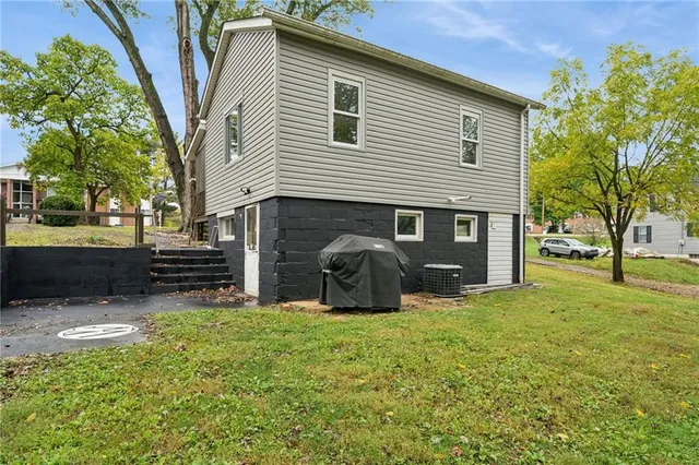 a view of a house with a yard and a large tree