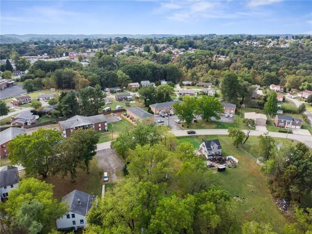 an aerial view of residential houses with outdoor space and trees