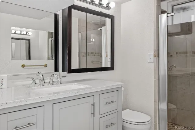 a bathroom with a granite countertop sink toilet and shower