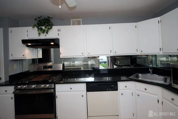 a kitchen with granite countertop white cabinets and black stainless steel appliances