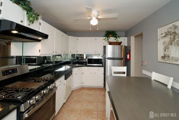 a kitchen with stainless steel appliances granite countertop a stove a refrigerator a sink a dining table and chairs with wooden floor