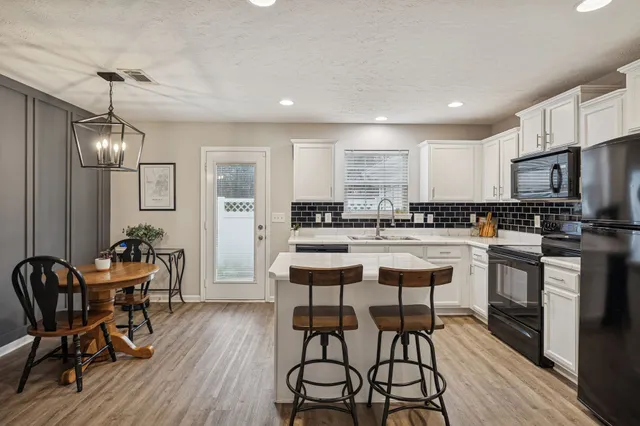 a kitchen with stainless steel appliances kitchen island granite countertop a dining table chairs refrigerator and sink