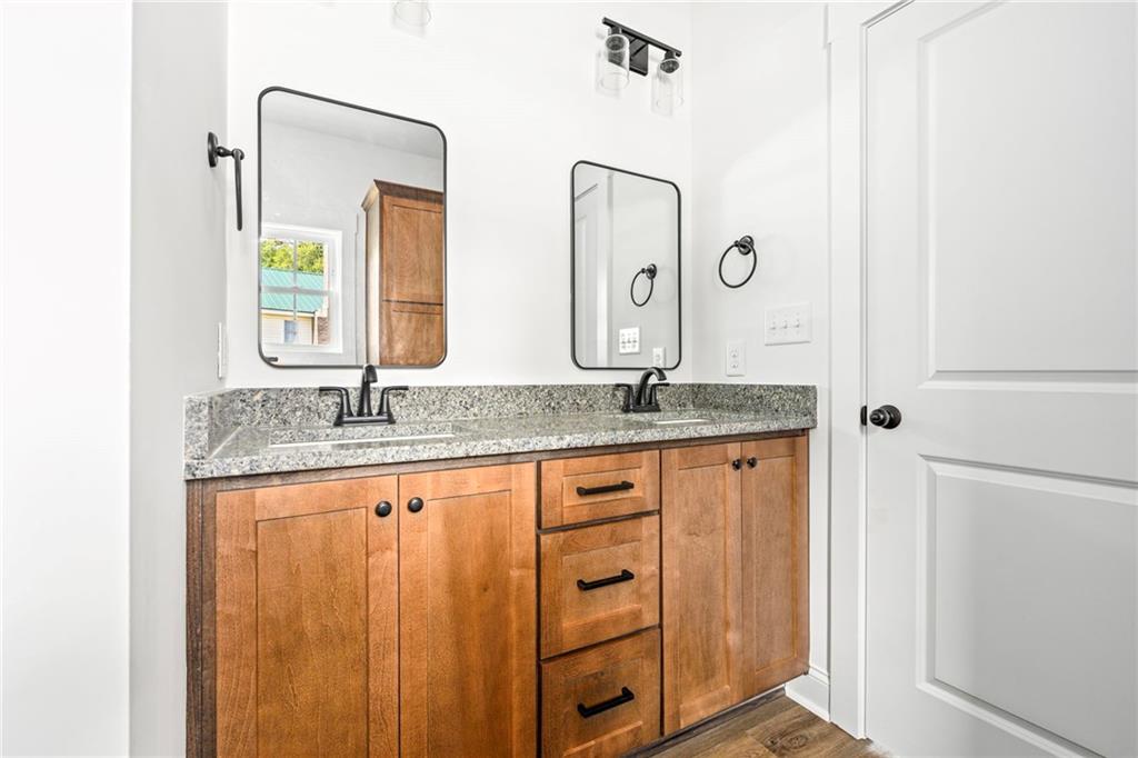 3216 South Phillips Road Lanett, AL 36863 - Photo 13 of 23 Dual vanity with wood cabinetry, stone countertop, matte black fixtures, and framed mirrors