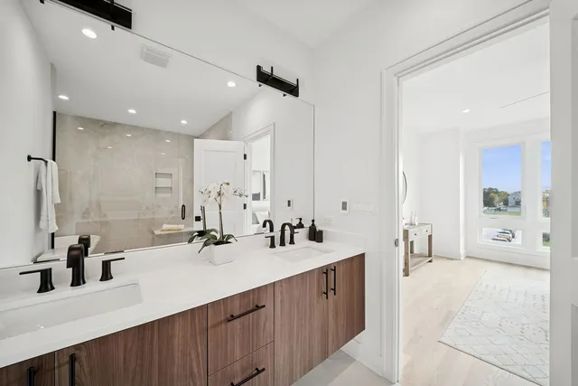 a bathroom with double vanity sinks a large mirror and shower