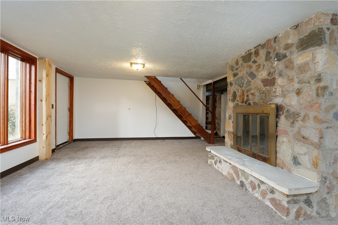 4491 Fox Road Kingsville, OH 44048 - Photo 27 of 33 Unfurnished living room featuring a fireplace, plenty of natural light, a textured ceiling, and carpet flooring