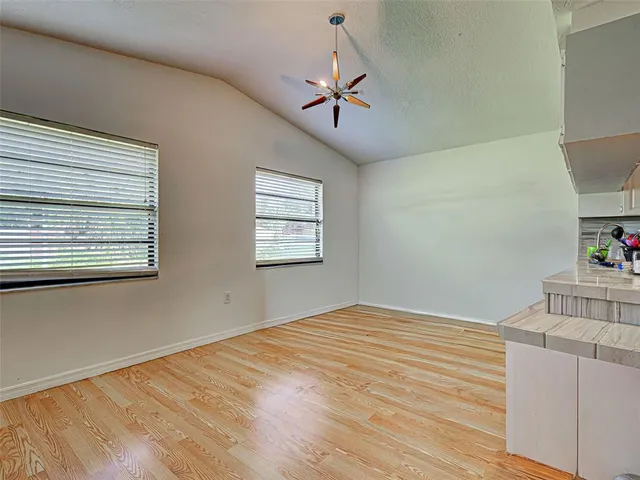 a view of empty room with wooden floor and fan