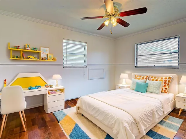 a bedroom with a bed a dresser and potted plant