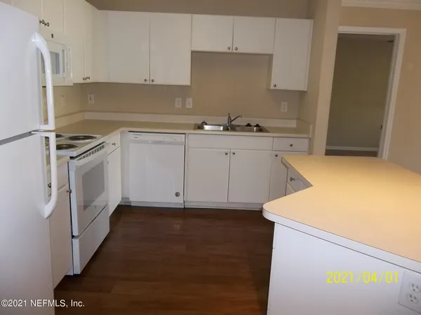 a kitchen with cabinets appliances and wooden floor