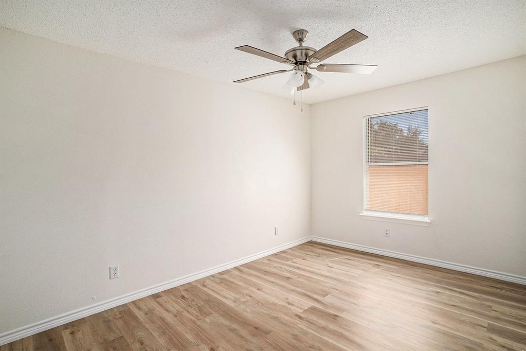 602 McAnear Street Cleburne, TX 76033 - Photo 19 of 27 an empty room with wooden floor window and ceiling fan