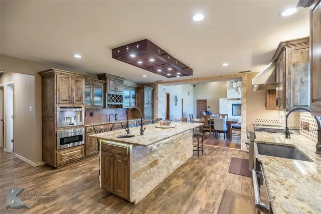 a large kitchen with stainless steel appliances granite countertop a sink stove and refrigerator