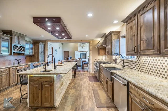 a large kitchen with stainless steel appliances kitchen island granite countertop a sink and cabinets