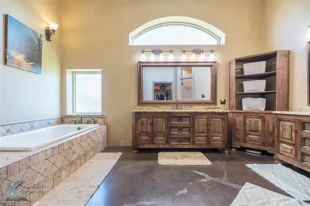a spacious bathroom with a tub double vanity and window